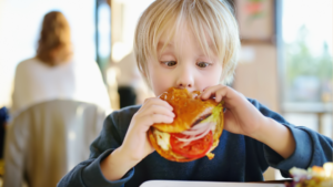 Niño celíaco comiendo hamburguesa fuera de casa